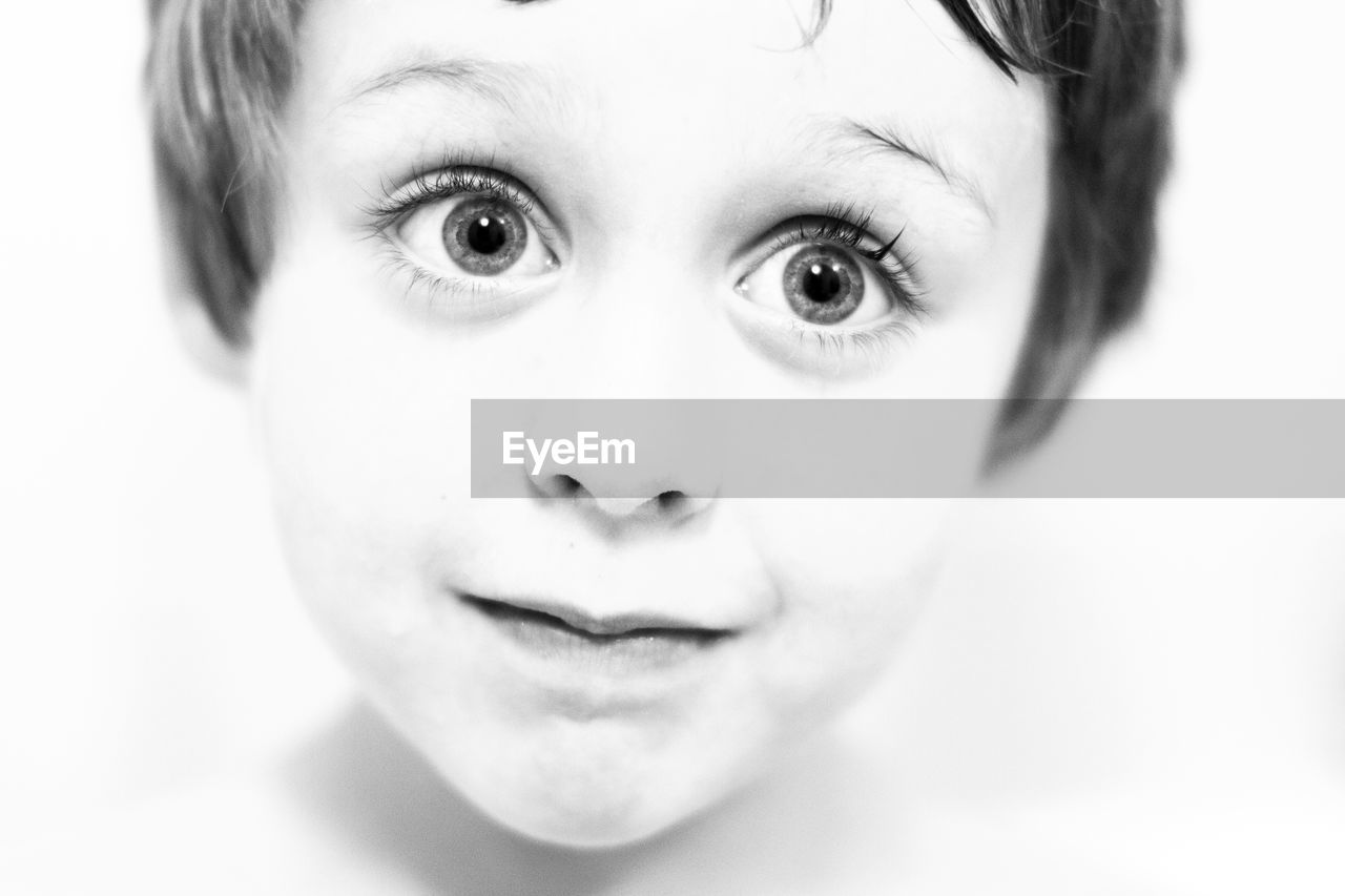 Close-up of cute boy with raised eyebrows against white background