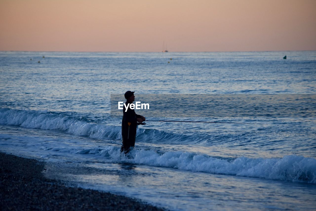 Side view of silhouette man fishing in sea