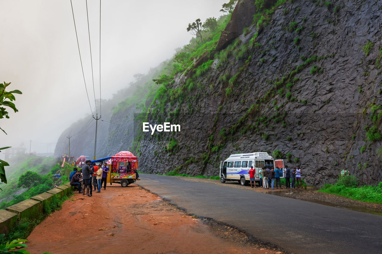 PEOPLE ON ROAD AGAINST MOUNTAIN