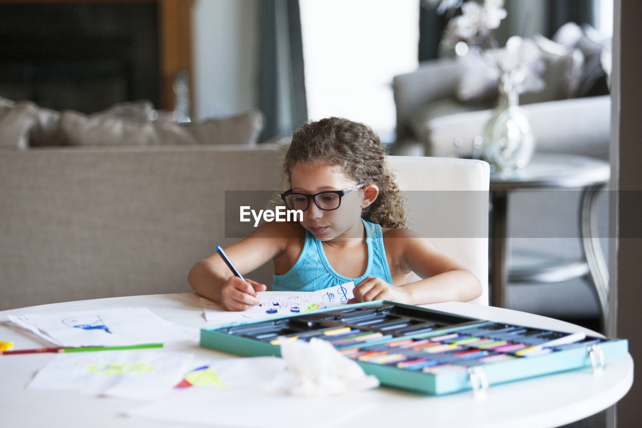 Girl coloring with felt tip pen on paper at table