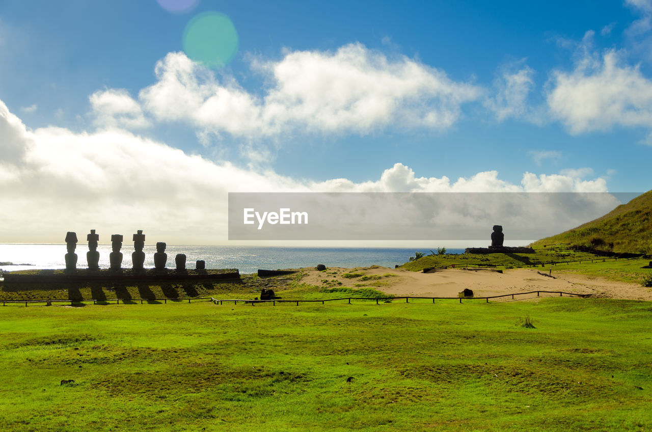 Moai statues at beach against sky