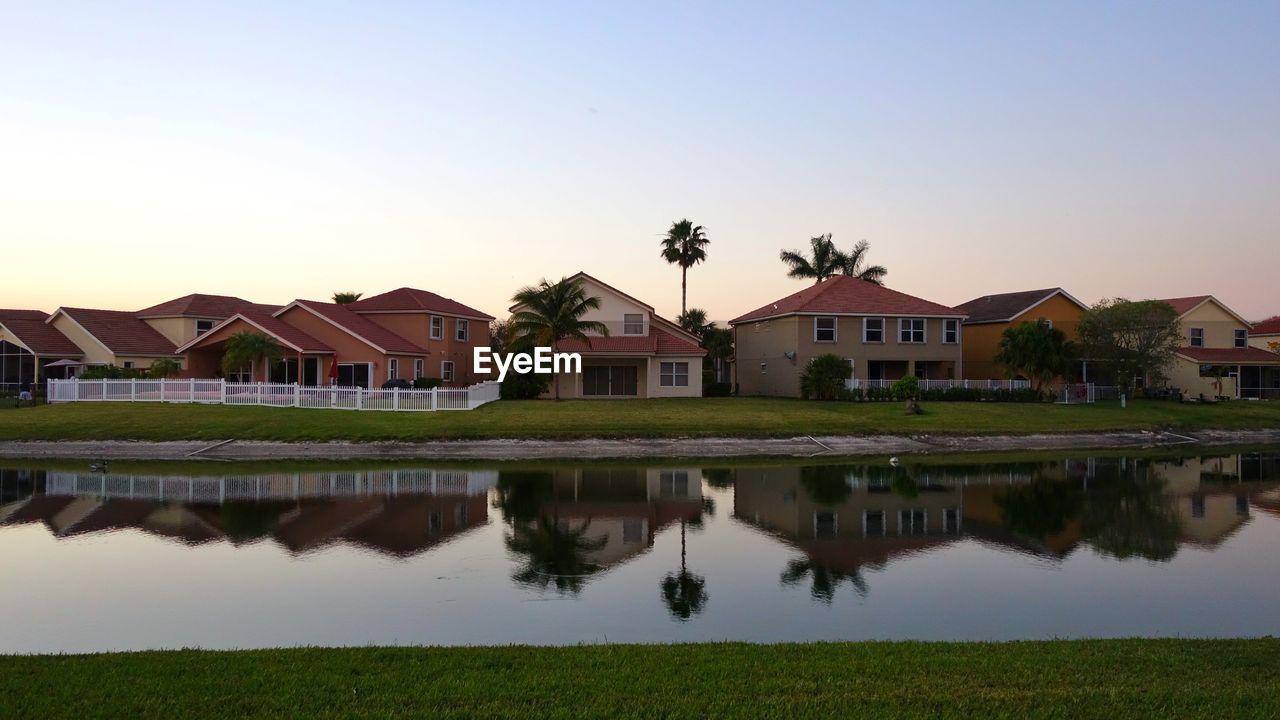 Reflection of houses in lake against clear sky