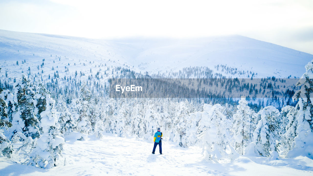 High angle view of man standing against on snowcapped mountain against sky