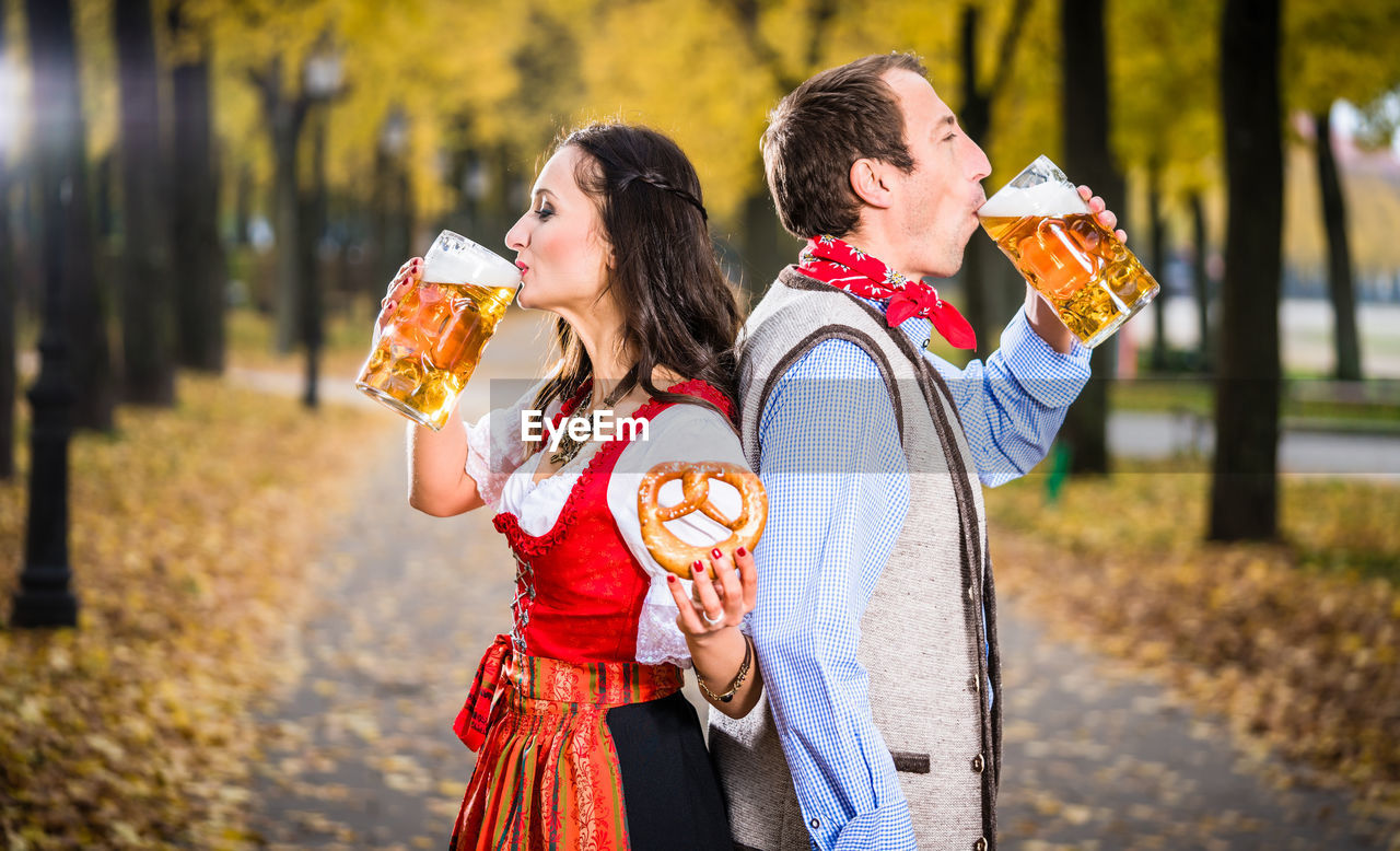 Couple drinking beer while standing at park during autumn