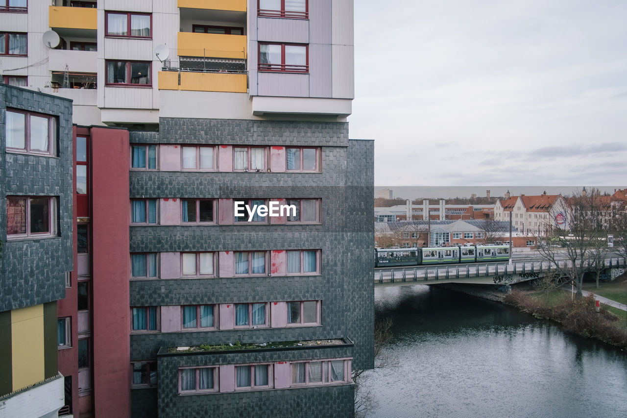 Buildings by river against sky in city