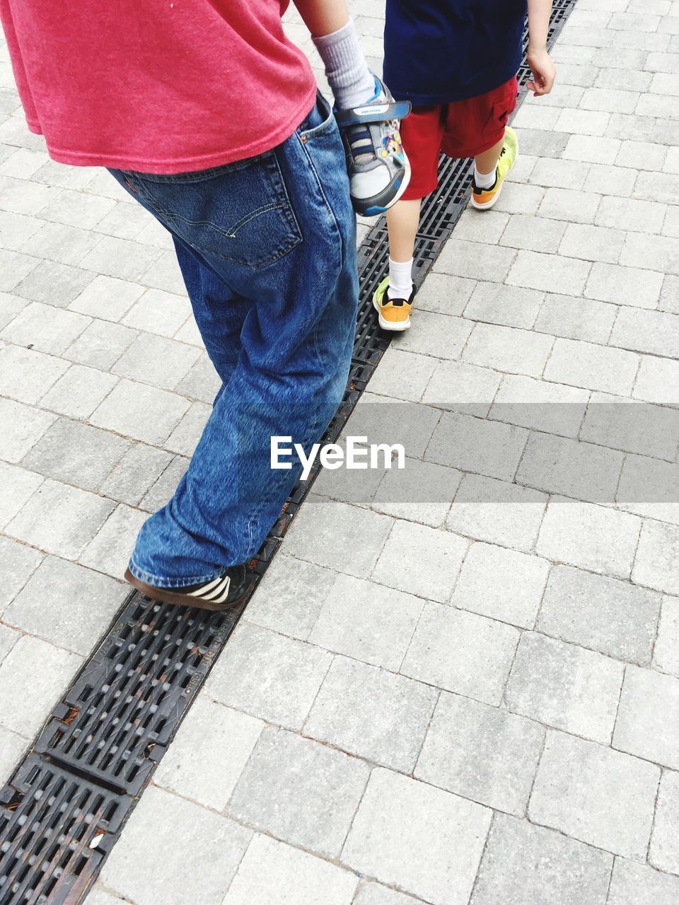 LOW SECTION OF MAN AND WOMAN WALKING ON SIDEWALK