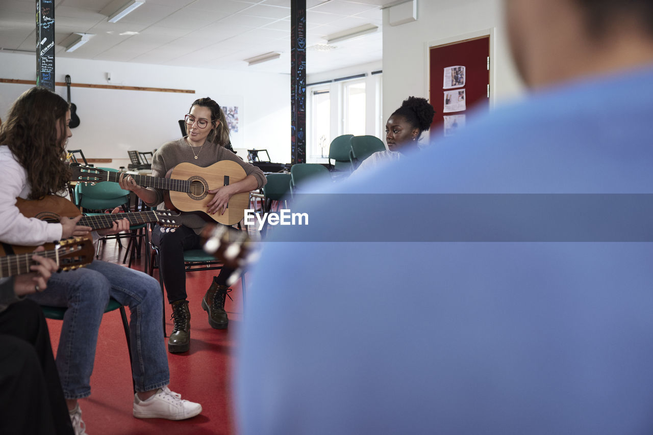 Teenagers attending guitar lesson