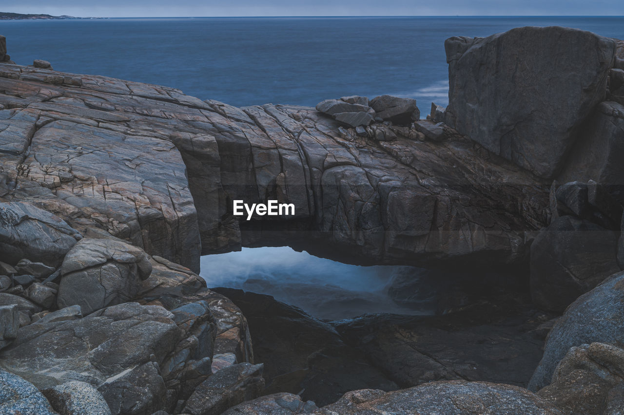 Rock formation by sea against sky