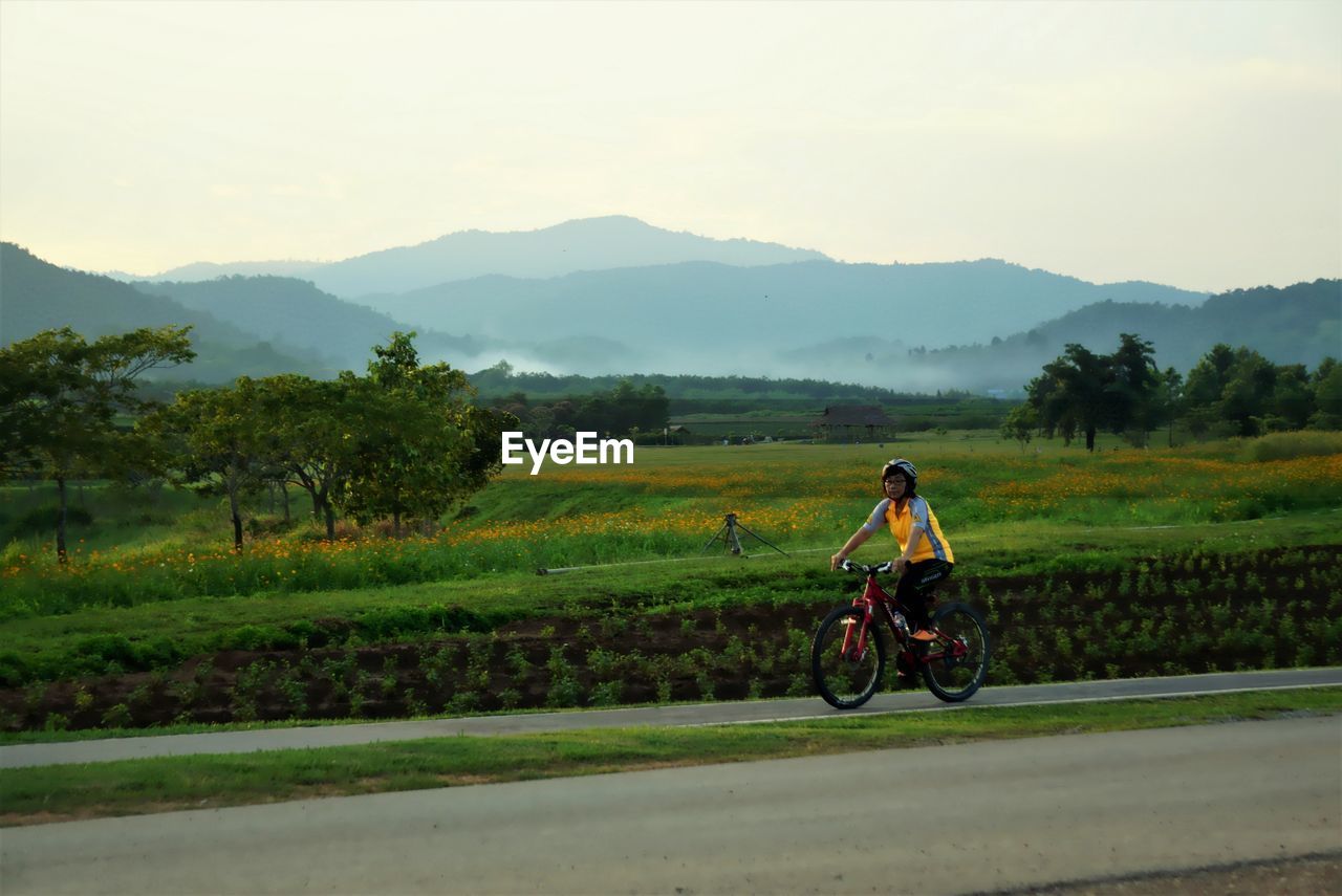 Woman riding bicycle on road against sky