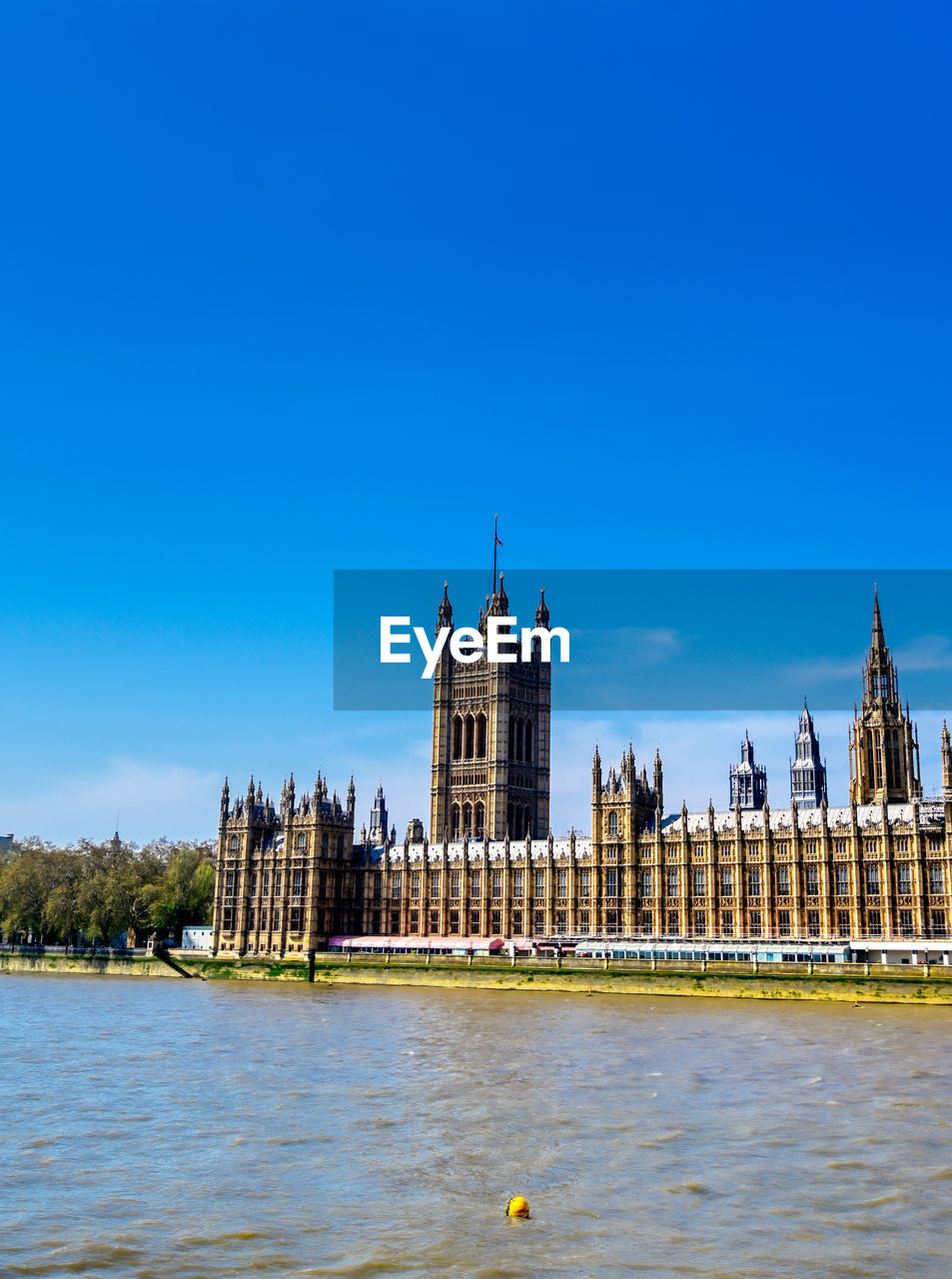 BUILDINGS BY RIVER AGAINST BLUE SKY