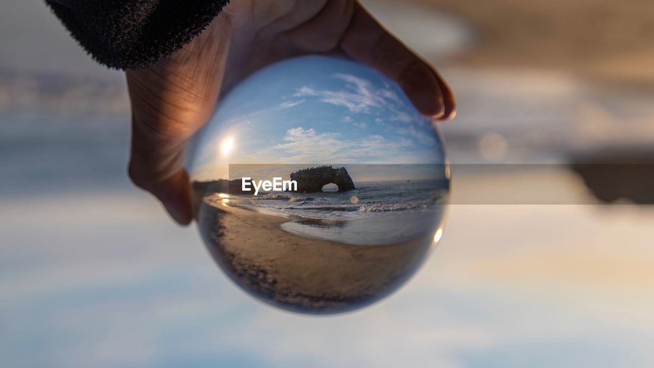 Close-up of hand holding crystal ball at beach