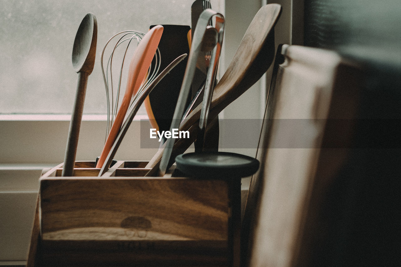 Close-up of kitchen utensils in wooden container at home