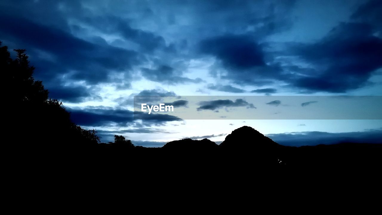 SILHOUETTE OF MOUNTAIN AGAINST CLOUDY SKY