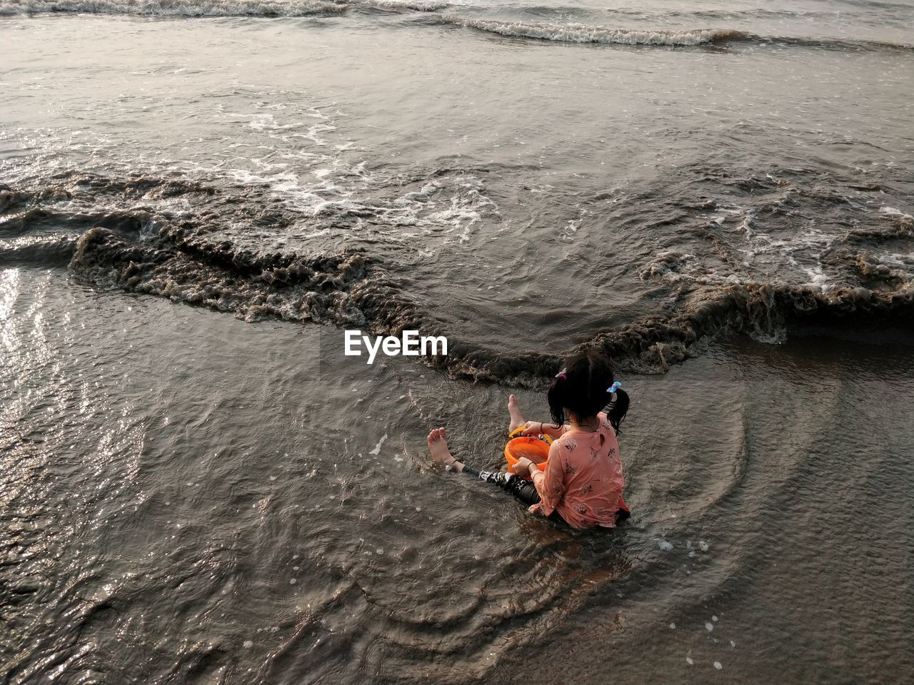 Rear view of girl sitting at sea