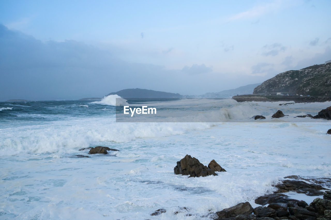 Waves breaking against the rocks of the coast of galicia forming foam