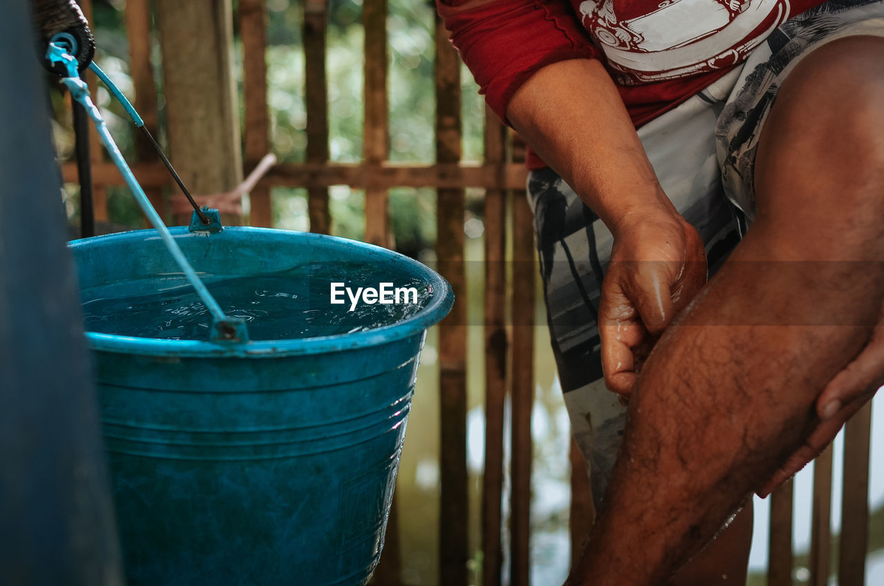 adult, one person, bucket, midsection, men, working, day, container, holding, occupation, food and drink, blue, lifestyles, nature, outdoors, water, hand, casual clothing, cleaning