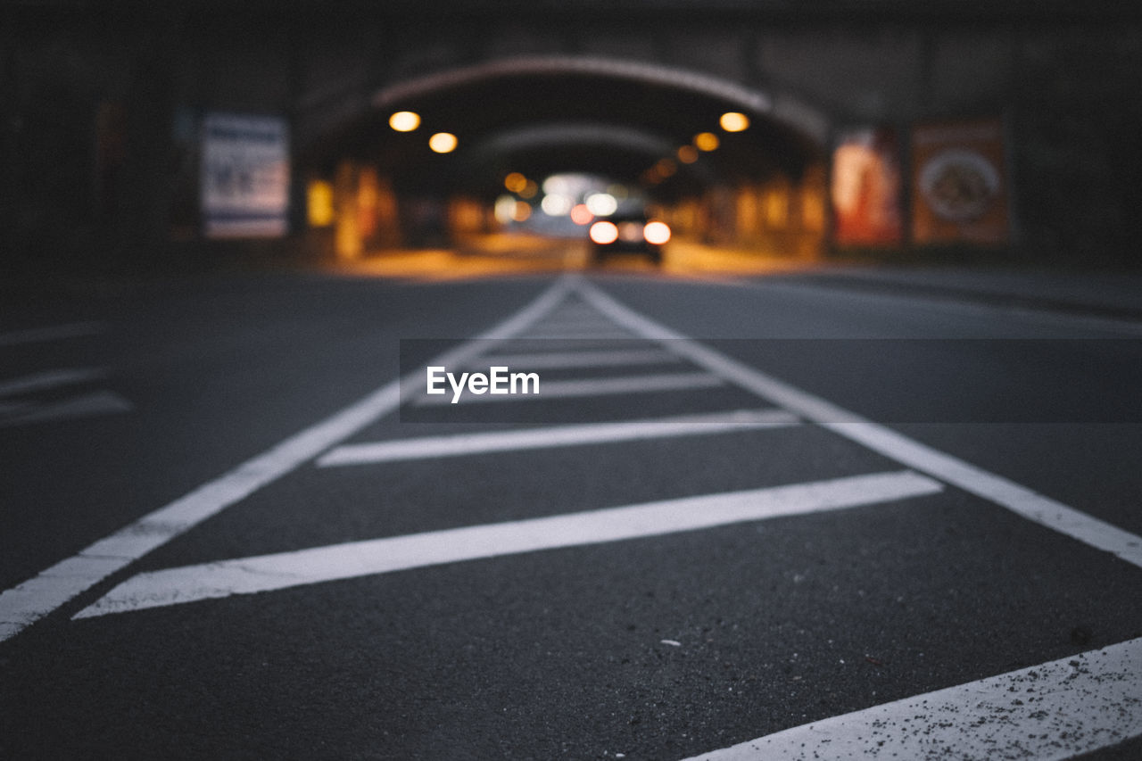 Close-up of zebra crossing on road at night