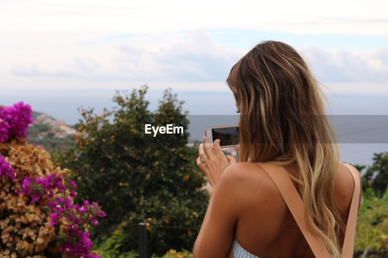 Rear view of woman photographing landscape