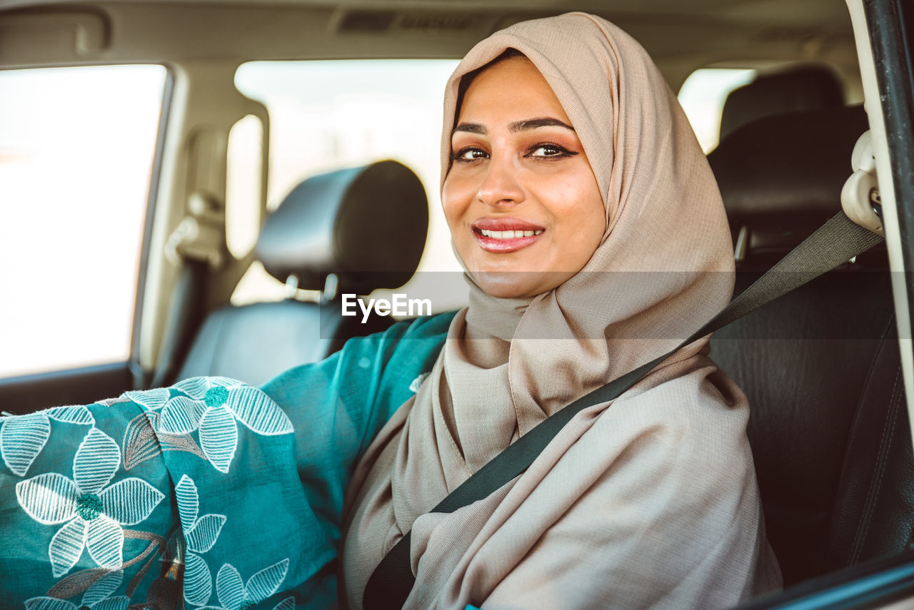 Portrait of smiling woman in hijab sitting in car