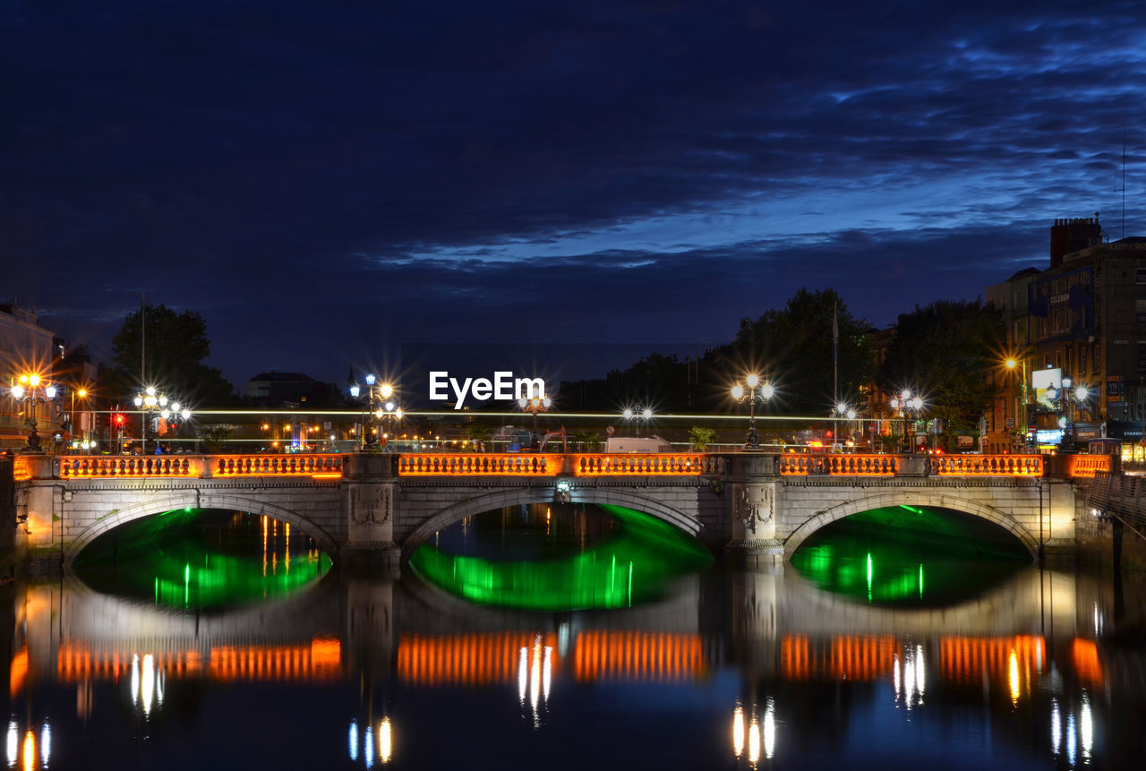 Illuminated bridge over river against sky at night