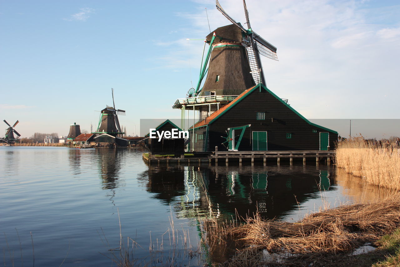 TRADITIONAL WINDMILL BY LAKE AGAINST SKY