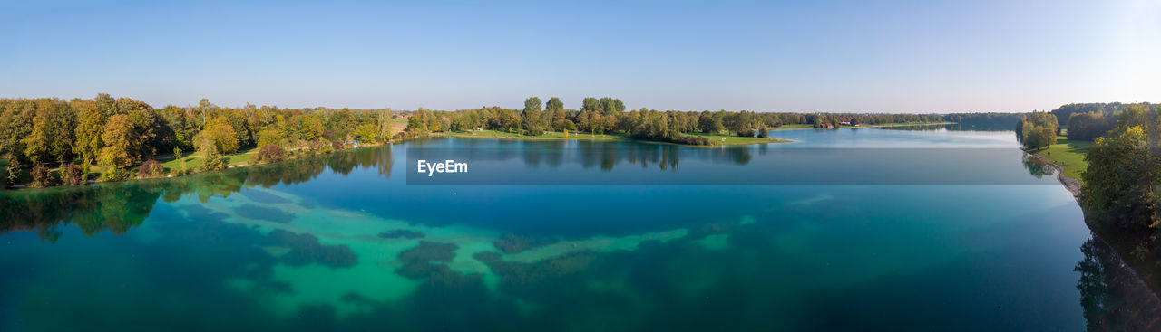 Aerial panoramia of lake karlsfeld with green and turquoise water against blue sky