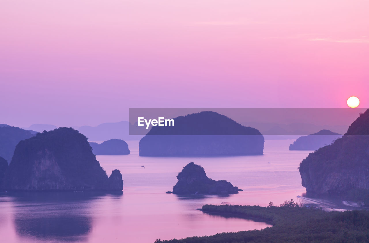 Rocks in sea against sky during sunset