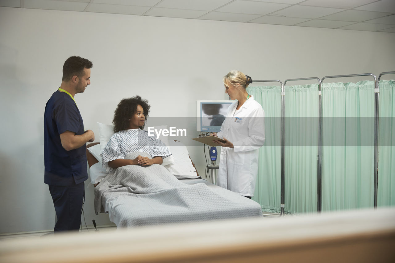 Doctor and nurse discussing with patient in medical room at hospital