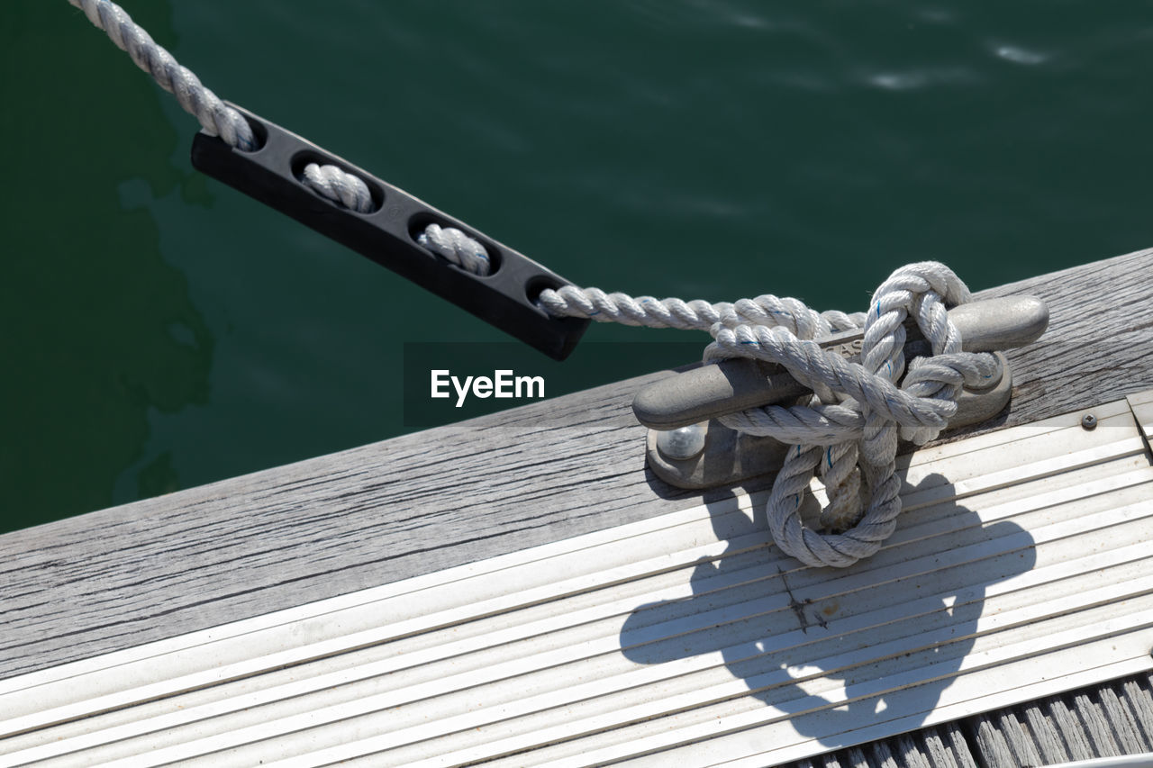 Close-up of rope tied on wood against sea