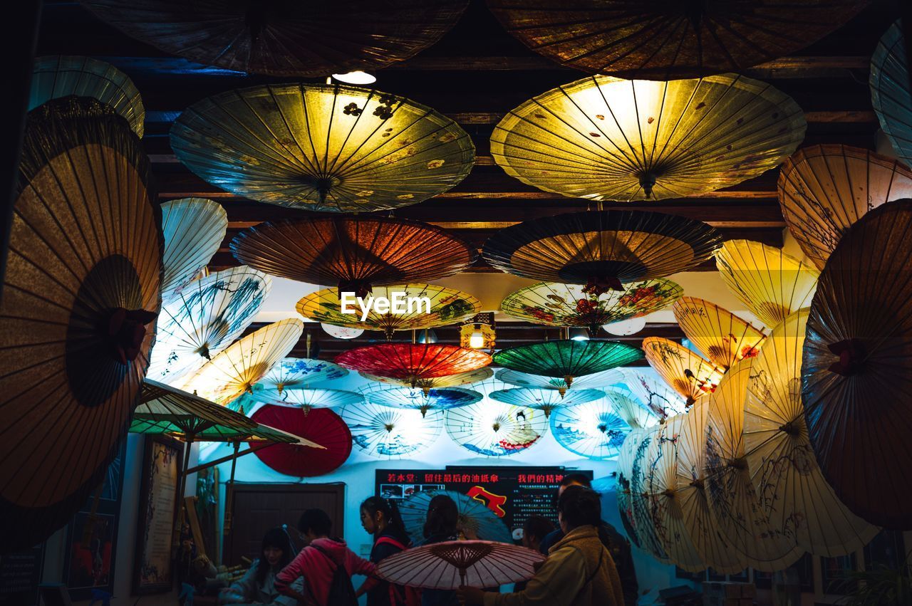 LOW ANGLE VIEW OF ILLUMINATED LANTERNS HANGING AT MARKET