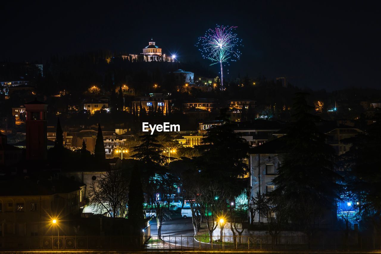 Firework display over illuminated buildings in city at night