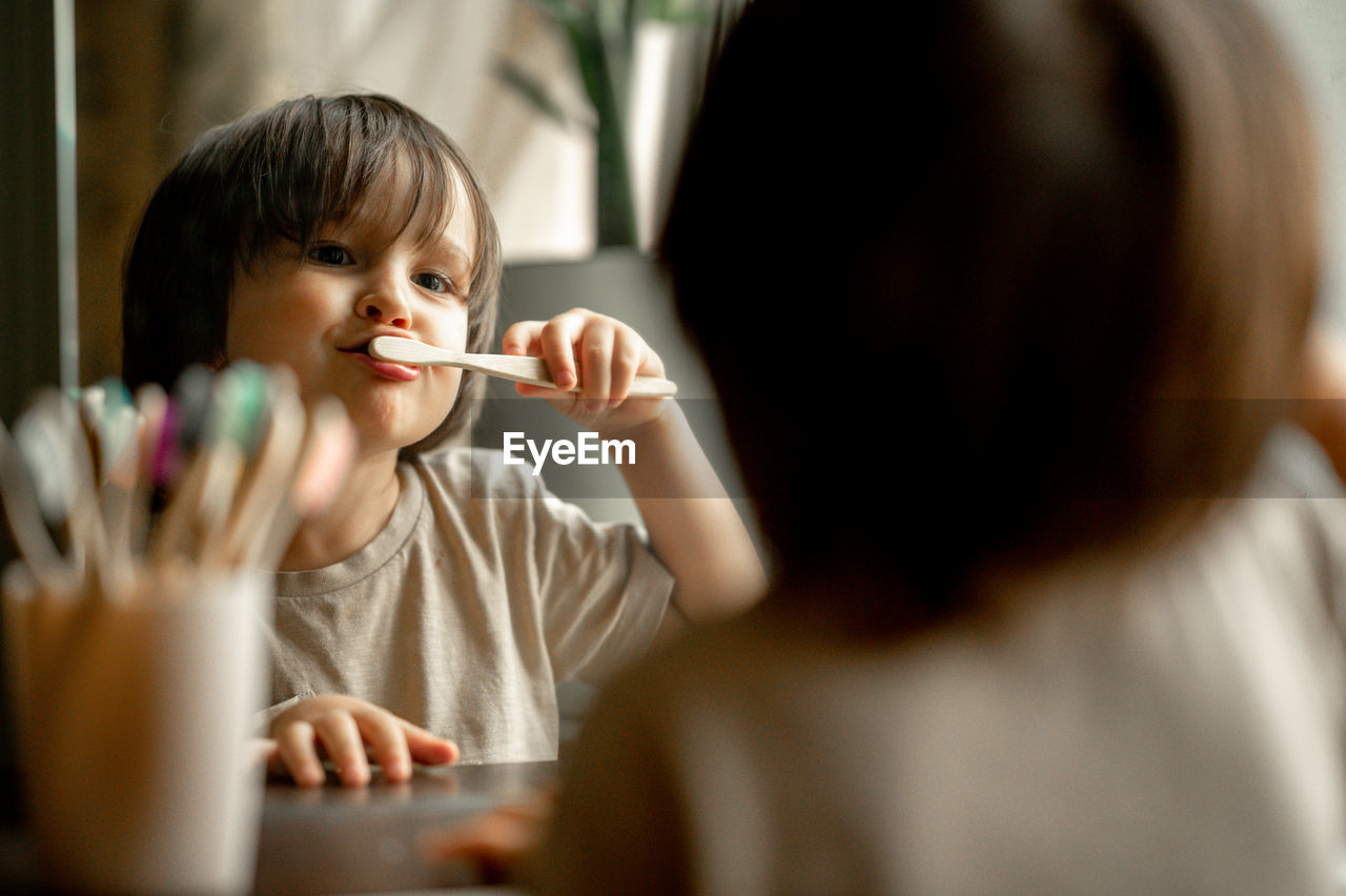 The boy brushes his teeth with a toothbrush made of ecological material