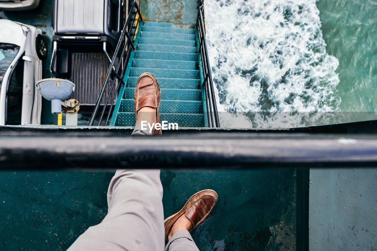 Low section of man standing on boat in sea