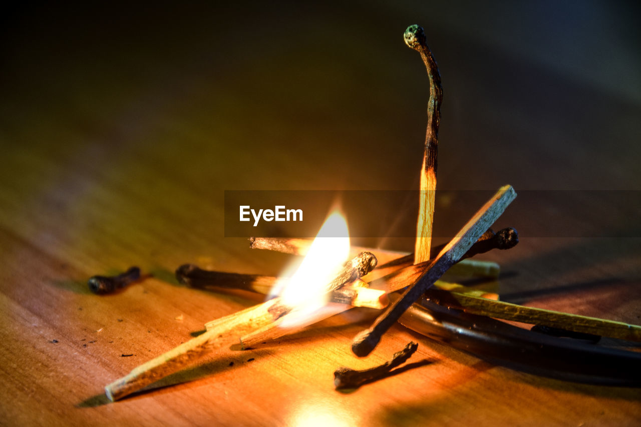 CLOSE-UP OF BURNING CANDLES ON WOOD