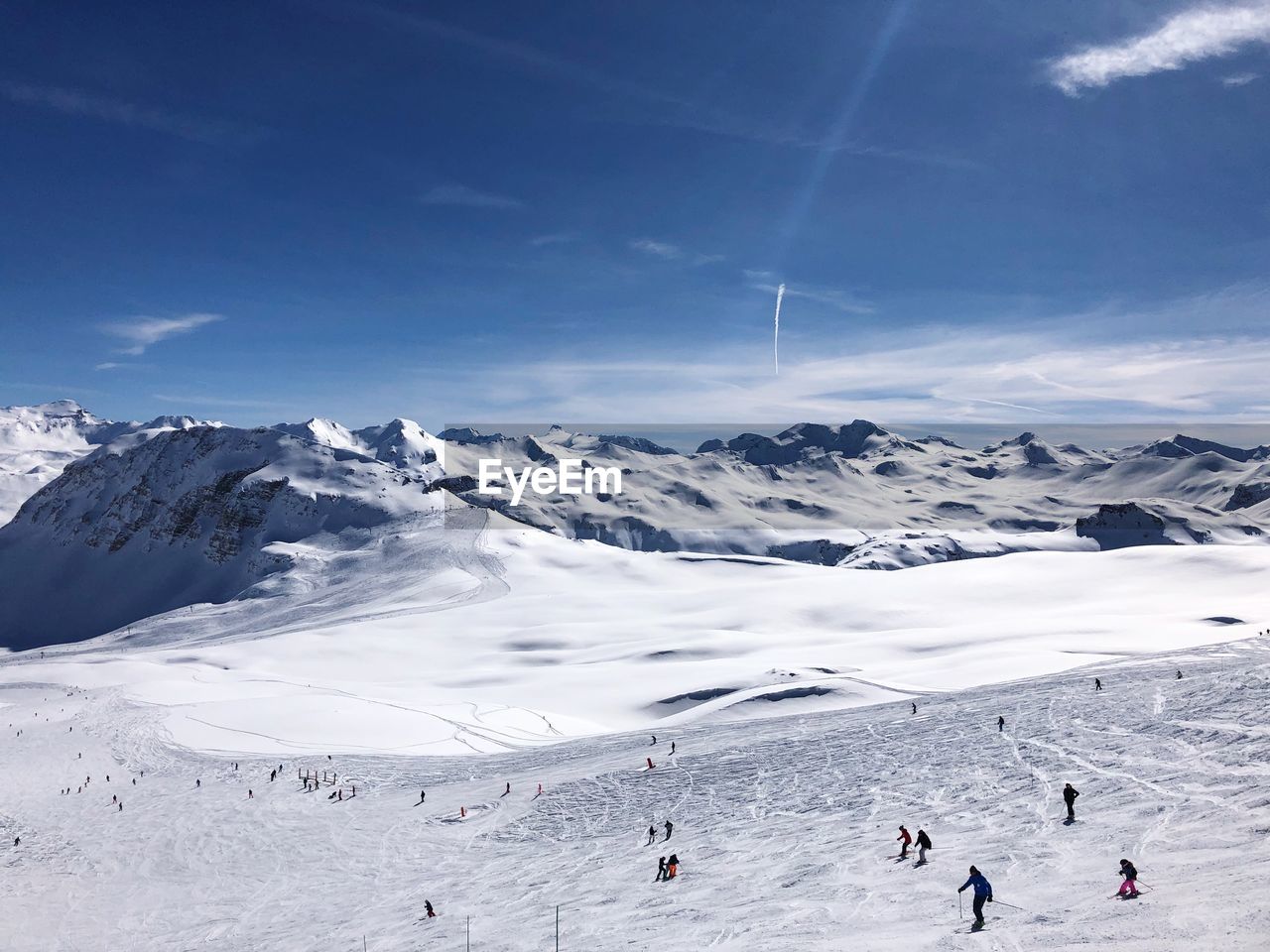 People skiing on landscape against sky during winter