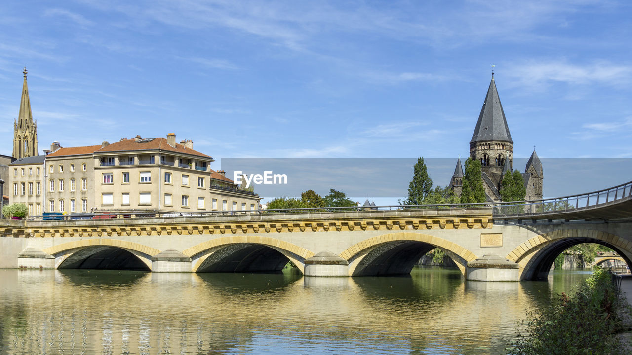 ARCH BRIDGE OVER RIVER BY BUILDINGS AGAINST SKY