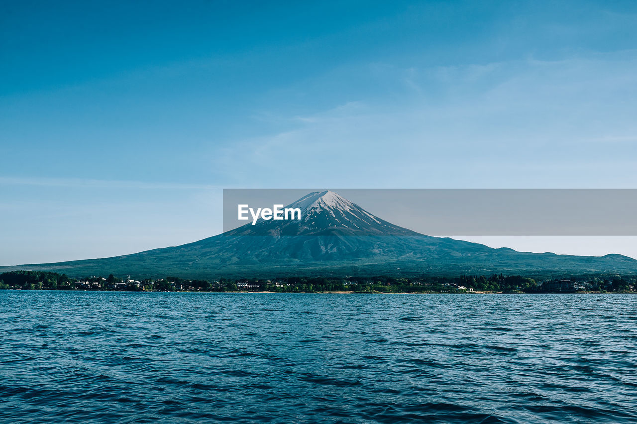 Scenic view of lake and snowcapped mt fuji against blue sky