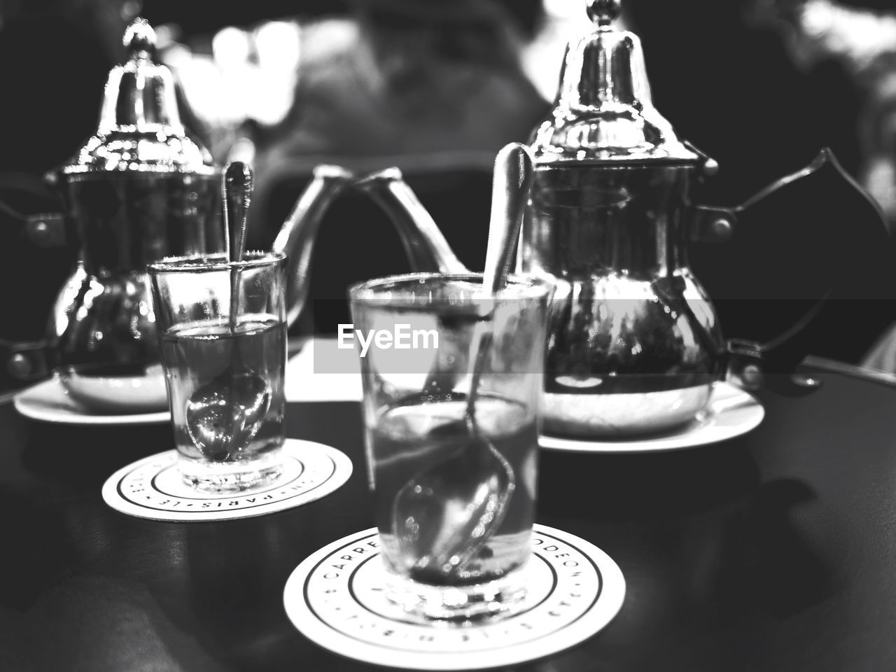 Spoons in drinking glass on table by jars