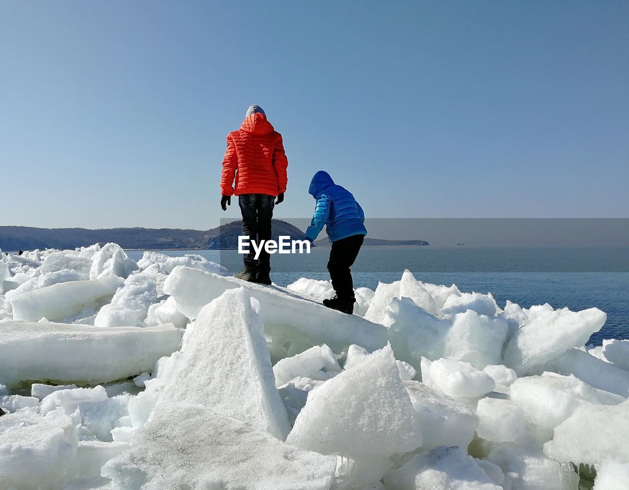 Siblings standing on ice at beach