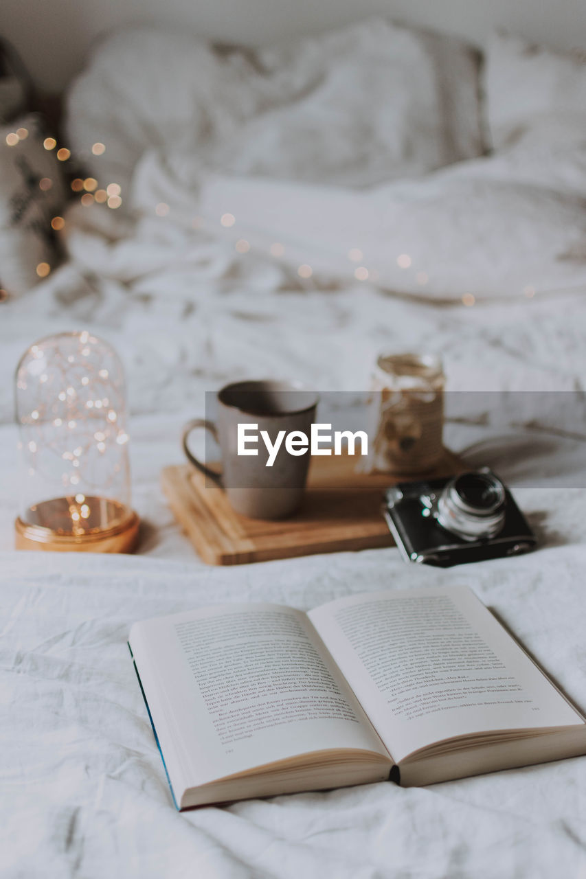 Coffee cup and book on bed at home