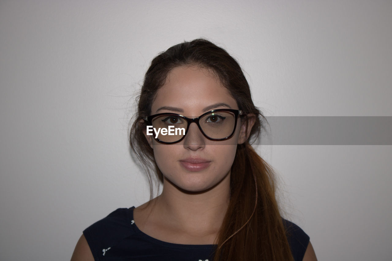 PORTRAIT OF YOUNG WOMAN WITH EYEGLASSES IN BACKGROUND