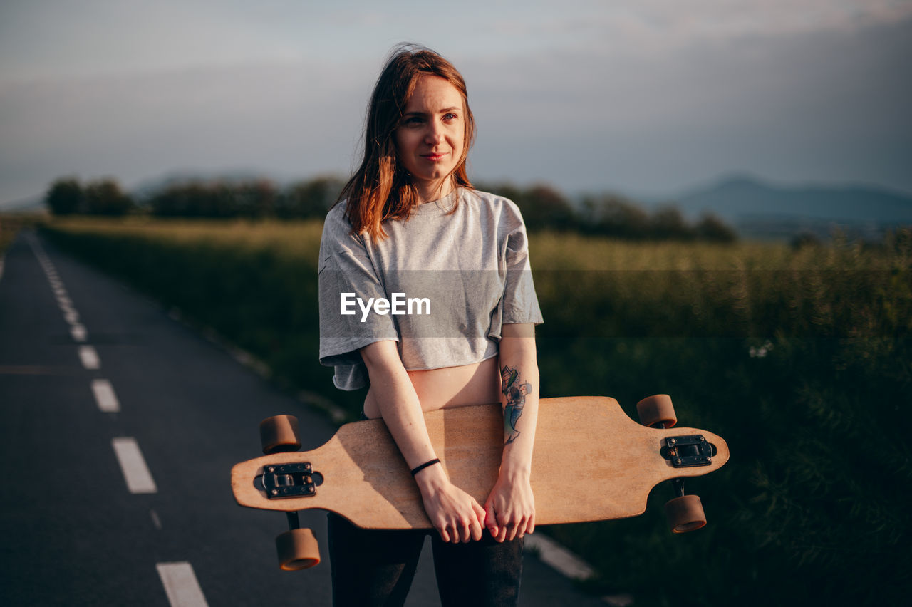 Young woman standing with skateboard