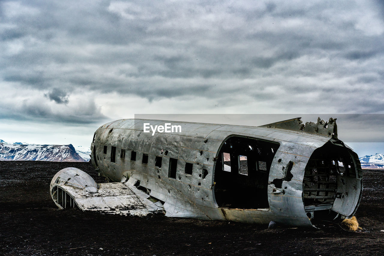 Crashed airplane on beach at solheimasandur against cloudy sky