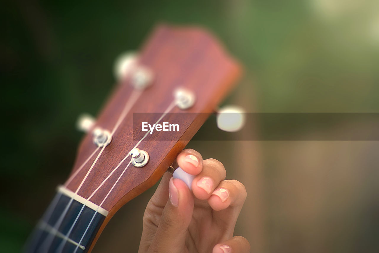 Cropped hand of woman adjusting guitar