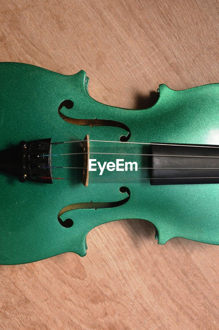 string instrument, violin, wood, musical instrument, music, bass guitar, green, bowed string instrument, musical equipment, arts culture and entertainment, indoors, viola, guitar, no people, musical instrument string, close-up, string, high angle view, still life, electric guitar, table