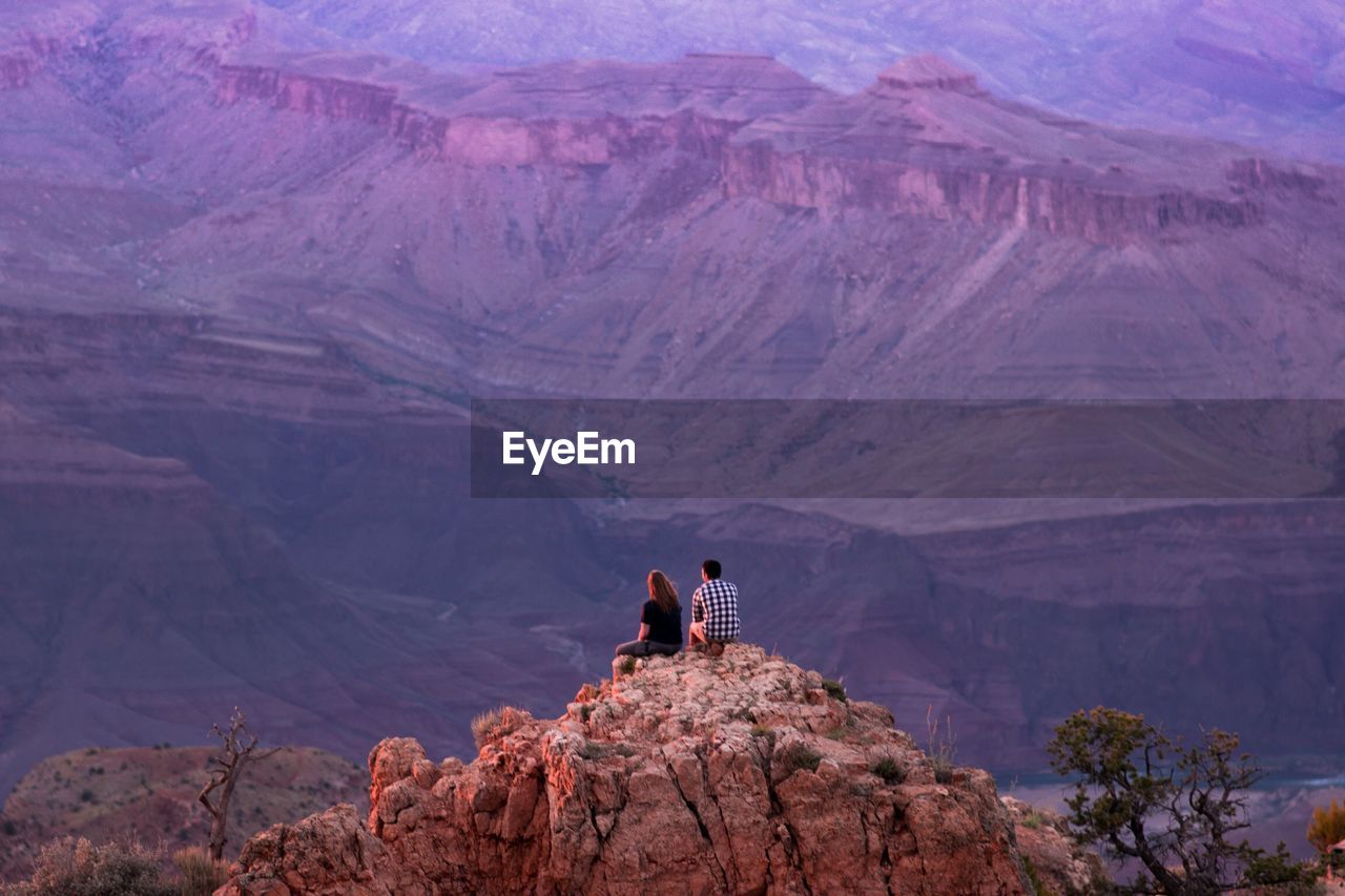 MAN ON ROCK BY MOUNTAIN