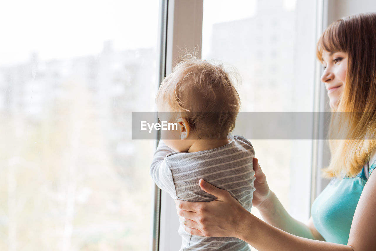 Mother and daughter against window