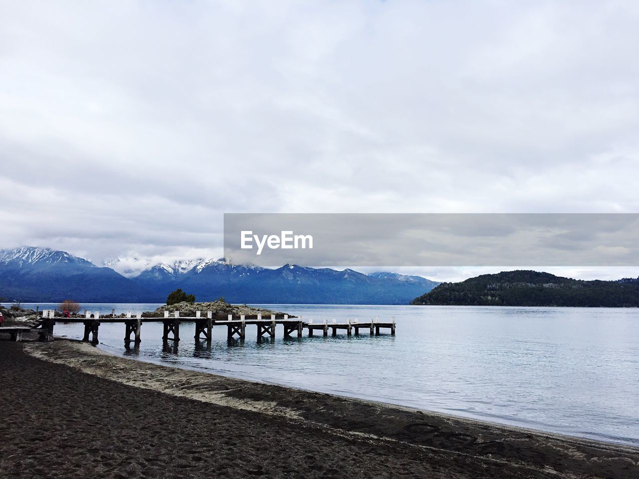 Scenic view of lake by mountains against cloudy sky