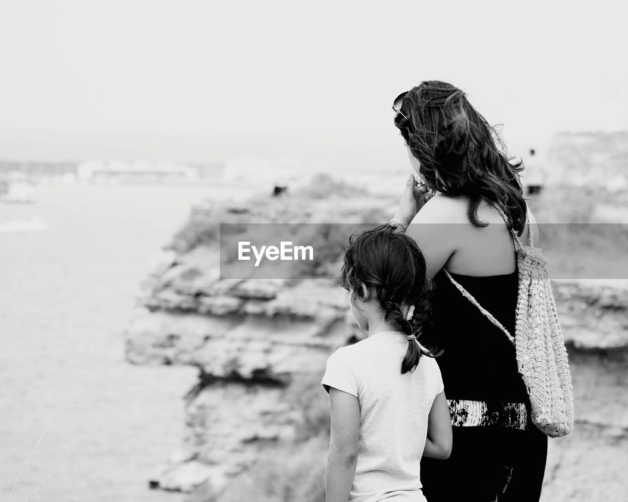 Rear view of mother with daughter standing on cliff