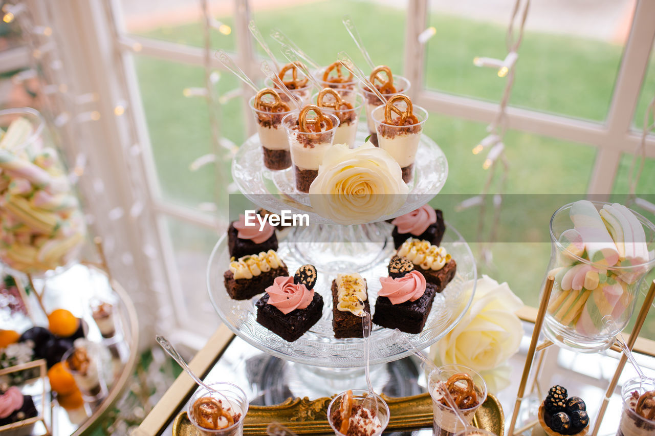 From above sweet delicious creamy chocolate cakes decorated with flowers on glass stand in cafe